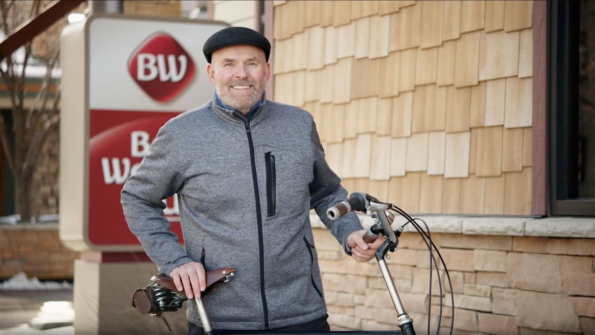 Man with a bike in front of a Best Western hotel sign
